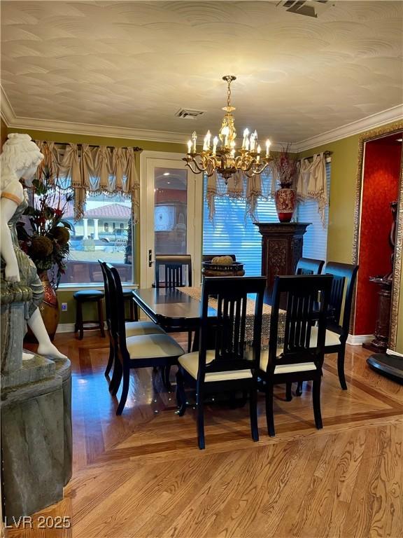 dining area with ornamental molding, parquet flooring, baseboards, and an inviting chandelier