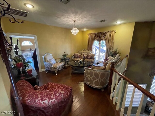 sitting room with a wealth of natural light, visible vents, wood finished floors, and an upstairs landing