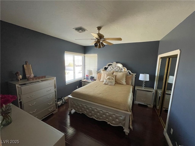 bedroom with wood-type flooring, visible vents, ceiling fan, and a textured ceiling