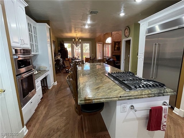 kitchen featuring stainless steel appliances, visible vents, dark wood-type flooring, and white cabinetry