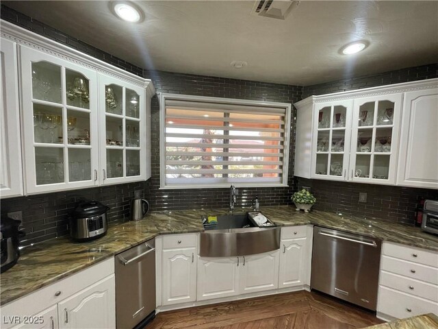 kitchen with dishwasher, a sink, white cabinets, and decorative backsplash