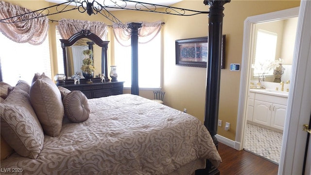 bedroom featuring dark wood finished floors, a sink, and ensuite bathroom