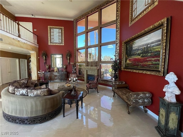 interior space featuring visible vents, baseboards, a premium fireplace, a high ceiling, and crown molding