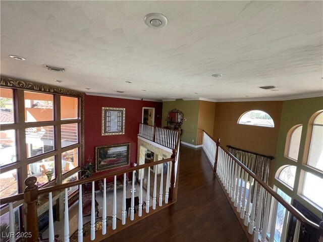 corridor with baseboards, visible vents, wood finished floors, crown molding, and an upstairs landing