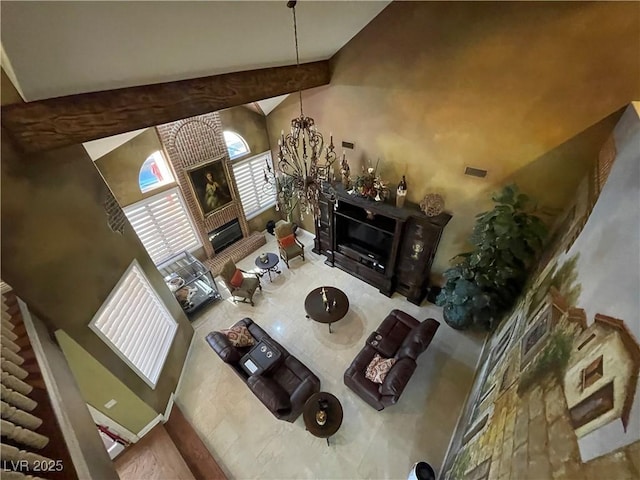 living room with high vaulted ceiling, visible vents, baseboards, a glass covered fireplace, and an inviting chandelier