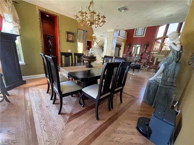 dining space with baseboards, visible vents, an inviting chandelier, and stairs