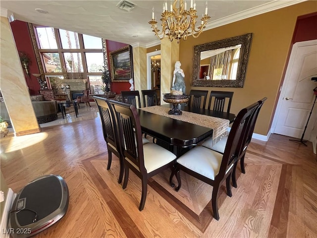 dining room with baseboards, visible vents, ornamental molding, wood finished floors, and a chandelier