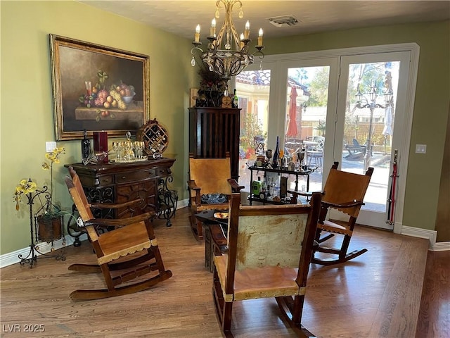 dining space with an inviting chandelier, baseboards, and wood finished floors