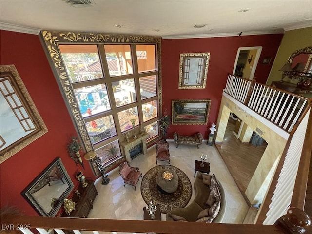 living area featuring a premium fireplace, visible vents, and crown molding