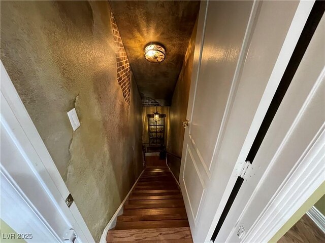 stairs with wood finished floors and a textured wall