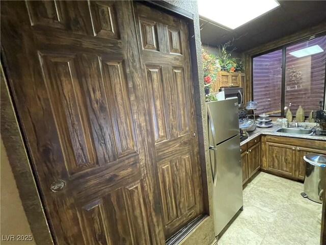 kitchen with stainless steel appliances, brown cabinets, light countertops, and a sink