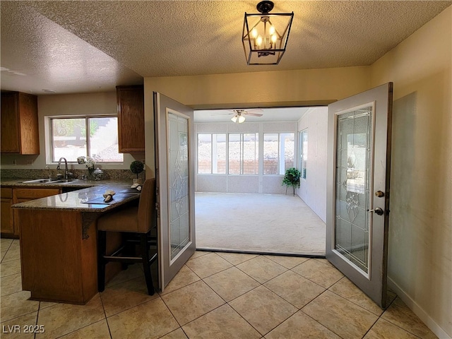 kitchen with decorative light fixtures, kitchen peninsula, a breakfast bar, sink, and light colored carpet