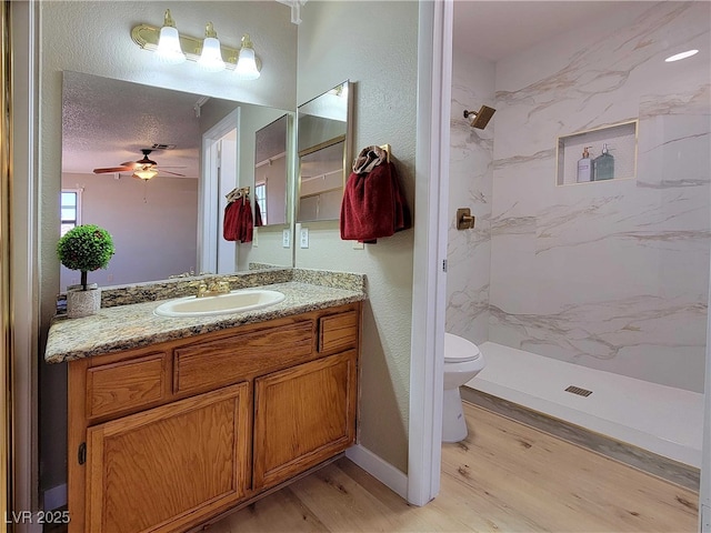 bathroom featuring ceiling fan, tiled shower, wood-type flooring, and vanity