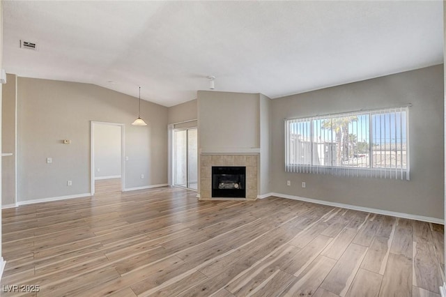 unfurnished living room featuring lofted ceiling, a fireplace, and light hardwood / wood-style flooring