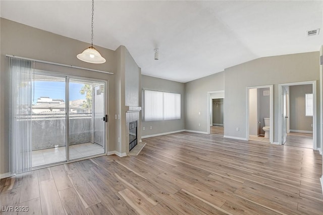 interior space featuring a tiled fireplace, hardwood / wood-style floors, vaulted ceiling, and plenty of natural light