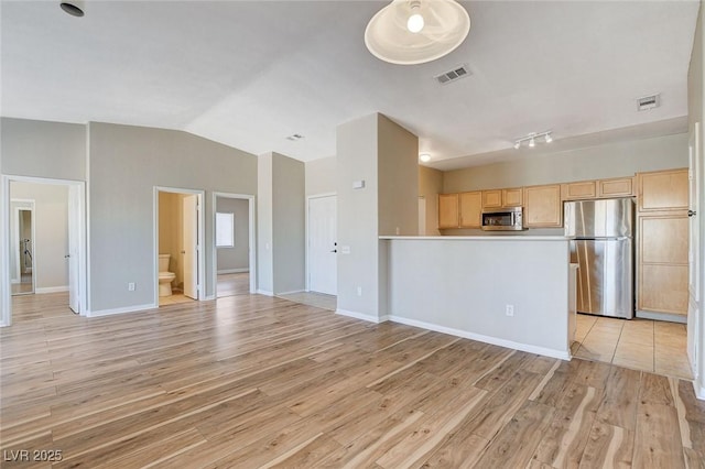 kitchen with lofted ceiling, light wood-type flooring, stainless steel appliances, and light brown cabinets