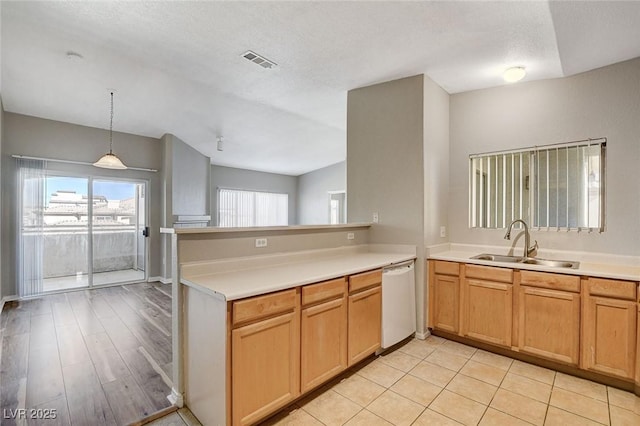 kitchen featuring dishwasher, sink, hanging light fixtures, kitchen peninsula, and a textured ceiling