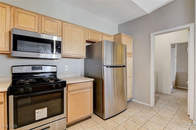 kitchen with light tile patterned floors, stainless steel appliances, and light brown cabinets