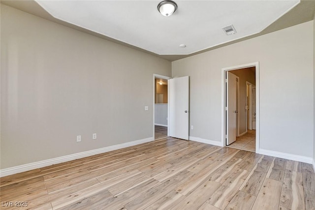 unfurnished bedroom with ensuite bathroom and light hardwood / wood-style floors