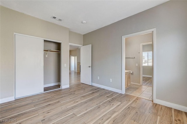 unfurnished bedroom featuring connected bathroom, light hardwood / wood-style floors, and a closet