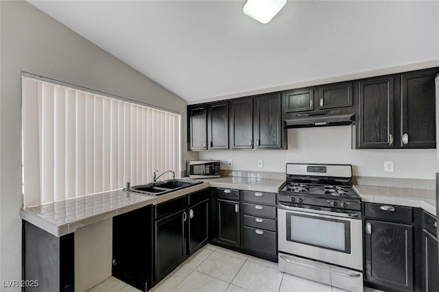 kitchen with stainless steel appliances, vaulted ceiling, sink, and light tile patterned flooring