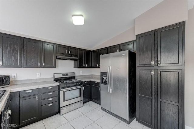 kitchen with light tile patterned floors, vaulted ceiling, and stainless steel appliances