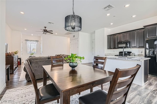 dining area featuring ceiling fan with notable chandelier and light hardwood / wood-style flooring