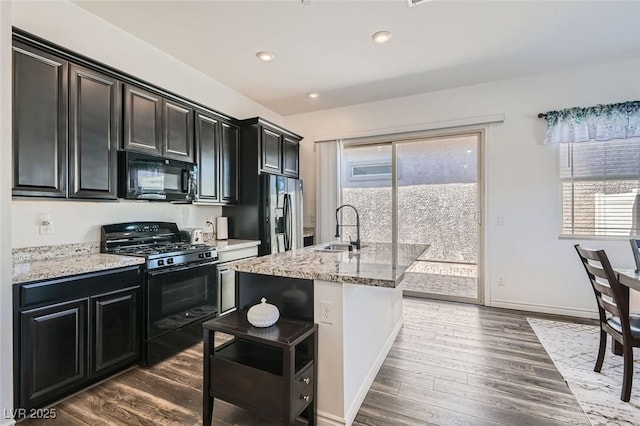 kitchen featuring a healthy amount of sunlight, sink, an island with sink, and black appliances