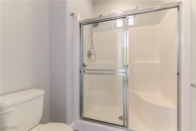 bathroom featuring toilet and a shower with shower door