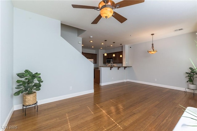 unfurnished living room featuring dark wood-type flooring and ceiling fan