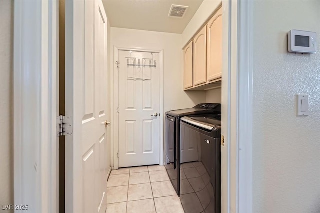 laundry area with cabinets, washing machine and clothes dryer, and light tile patterned flooring