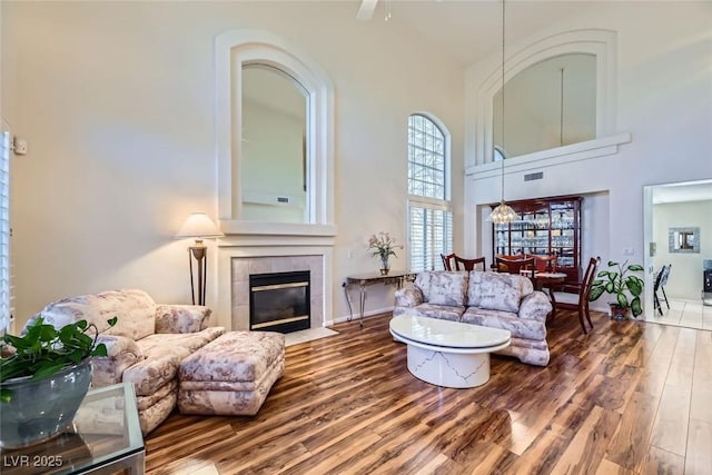 living room with a towering ceiling, a fireplace, and hardwood / wood-style floors