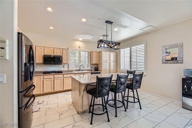 kitchen with pendant lighting, appliances with stainless steel finishes, a center island, and light brown cabinets