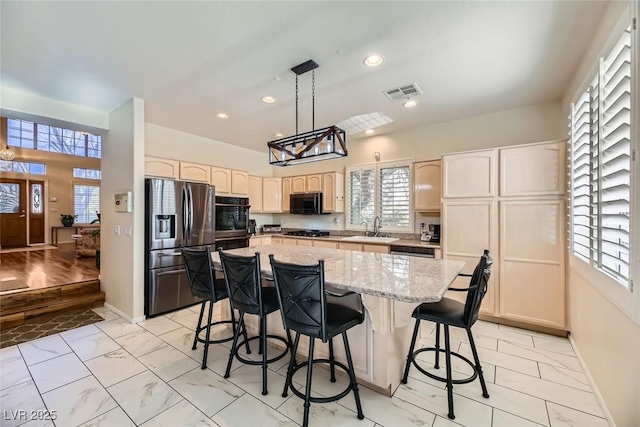 kitchen featuring hanging light fixtures, plenty of natural light, black appliances, and a center island