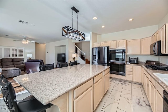 kitchen with a kitchen bar, decorative light fixtures, a kitchen island, ceiling fan, and stainless steel appliances