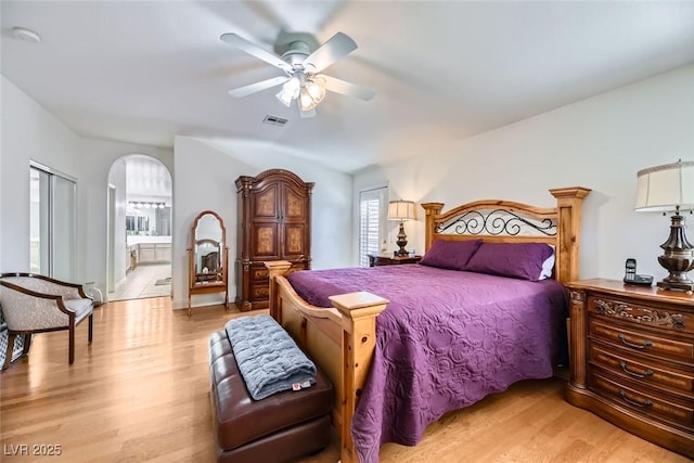 bedroom featuring ceiling fan, light wood-type flooring, and ensuite bath