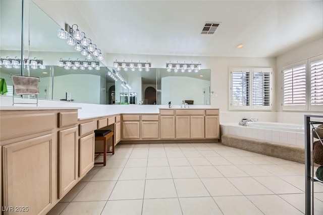 bathroom featuring tile patterned flooring, vanity, and tiled tub