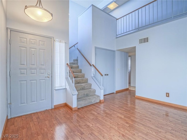 entrance foyer with a towering ceiling and light wood-type flooring