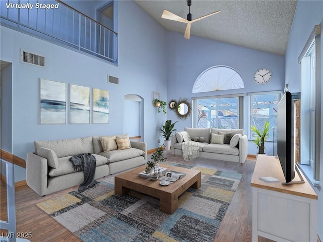 living room featuring hardwood / wood-style flooring, high vaulted ceiling, and a textured ceiling