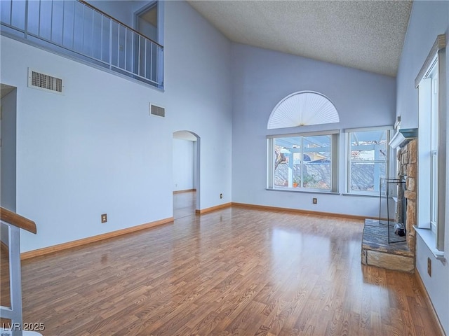 unfurnished living room with hardwood / wood-style flooring, high vaulted ceiling, and a textured ceiling