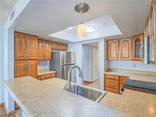 kitchen featuring sink, hanging light fixtures, a tray ceiling, kitchen peninsula, and stainless steel appliances