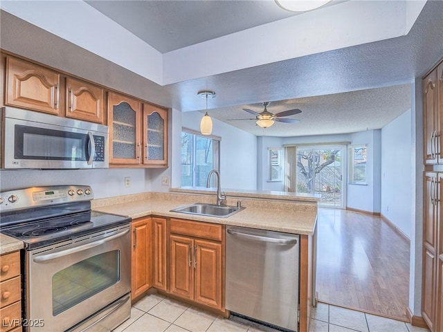 kitchen with appliances with stainless steel finishes, kitchen peninsula, sink, and plenty of natural light