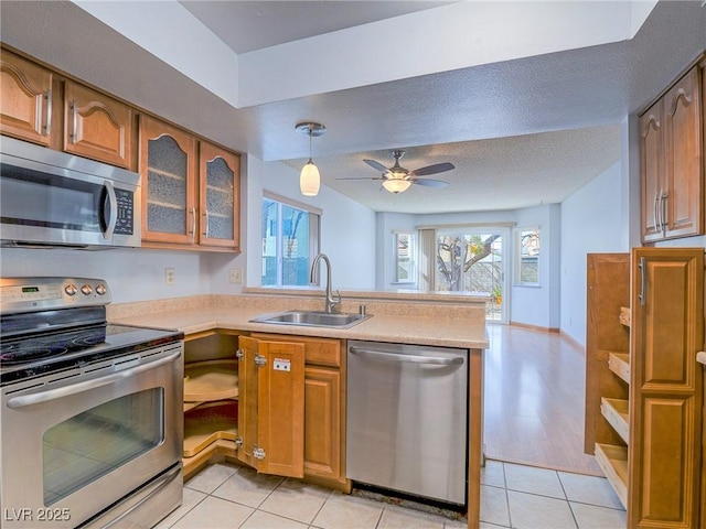 kitchen with appliances with stainless steel finishes, decorative light fixtures, sink, light tile patterned floors, and a textured ceiling