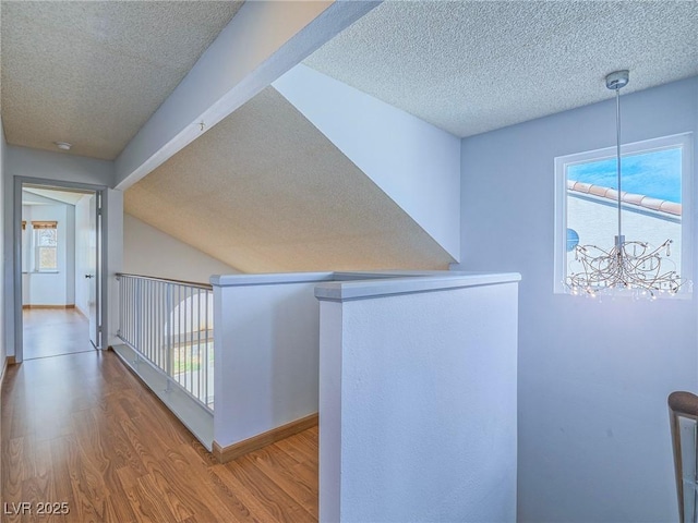 hall featuring an inviting chandelier, a wealth of natural light, hardwood / wood-style floors, and a textured ceiling