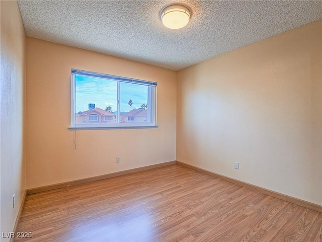 unfurnished room with light hardwood / wood-style flooring and a textured ceiling