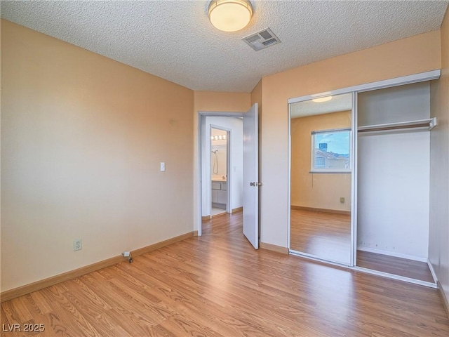 unfurnished bedroom featuring a textured ceiling, light hardwood / wood-style floors, and a closet