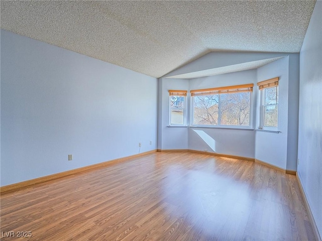 spare room with lofted ceiling, hardwood / wood-style floors, and a textured ceiling