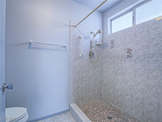 bathroom with a tile shower, tile patterned floors, and toilet