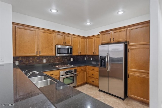 kitchen featuring sink, light tile patterned floors, appliances with stainless steel finishes, dark stone countertops, and decorative backsplash