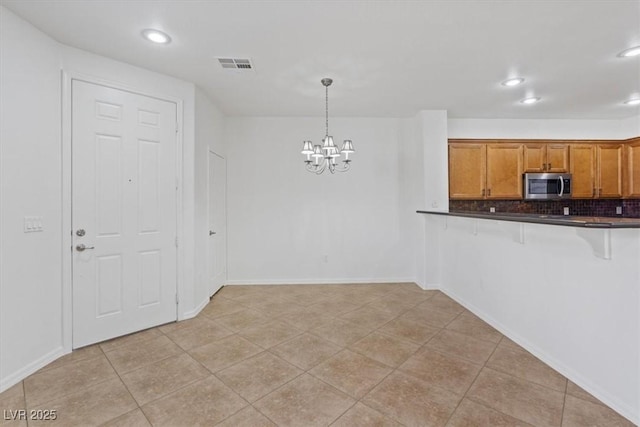 kitchen featuring pendant lighting, light tile patterned floors, tasteful backsplash, a kitchen bar, and a chandelier